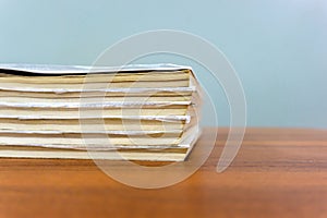 A stack of books are lying on a brown table, documents are stacked close-up