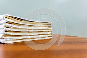 A stack of books are lying on a brown table, documents are stacked close-up