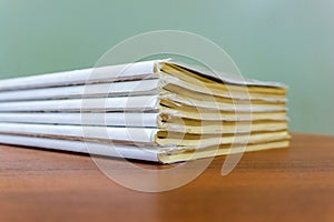A stack of books are lying on a brown table, documents are stacked close-up