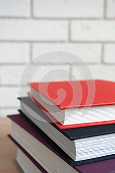 A stack of books with multi-colored covers on the table with blurred background