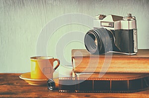 Stack of books, old clock and vintage camera over wooden table. image is processed with retro faded style