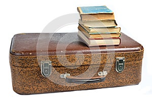 A stack of books on an old leather suitcase isolated on a white background