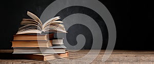 Stack of Vintage Books with Open Pages on Wooden Table