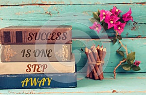 Stack of books over wooden table and motivational phrase