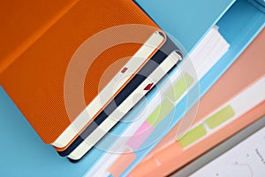 Stack of books with paper foder lie in office against