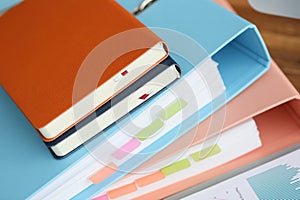 Stack of books with paper foder lie in office against