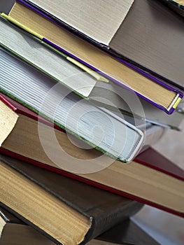 A stack of books photographed at an angle. Thick books in a stack are shifted relative to each other. Close-up.