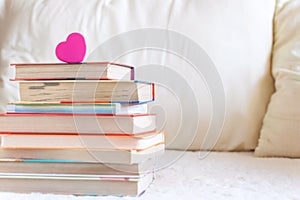 Stack of books and pink heart on the white bed. Education background with Copy space, back to school concept