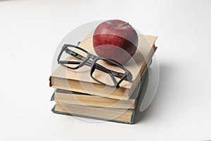 stack of books, red apple and glasses isolated on colorful surface, simple abstract study concept