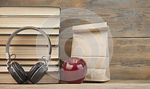 Stack of books with red apple and headphone  on the wood table with copyspace