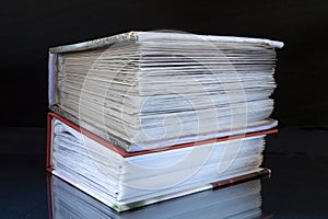 Stack of the books rests upon turn blue table with reflection