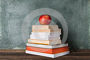 Stack of books and stationery on the background of the school board