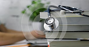 Stack of books with stethoscope and medical student