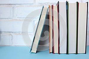 Stack of books on the table against white brick wall. Back to school background.