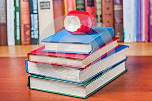 Stack of books on the table and red apple