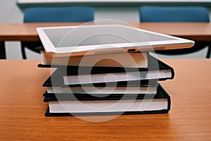 Stack of books and tablet on the table.