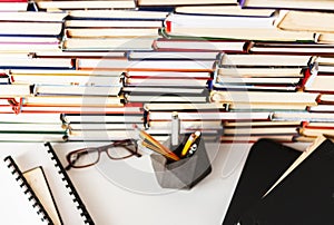 Stack of books, textbook, laptop, glasses in office business background for education learning concept