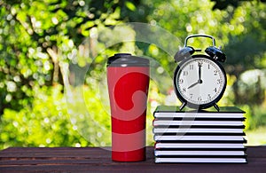 A stack of books, a thermo mug and an alarm clock. School concept. Work and education. Copy space