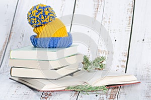 Stack of books with winter hat on top on wooden background
