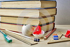 a stack of books writing materials stationery clips and a split chicken egg with the letter A inside on the table the