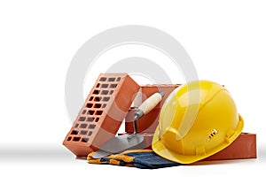 Stack of bricks with masonry trowel,  construction hard hat and gloves on white background. Construction concept