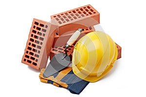 Stack of bricks with masonry trowel,  construction hard hat and gloves on white background. Construction concept