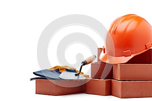 Stack of bricks with masonry trowel,  construction hard hat and gloves on white background. Construction concept