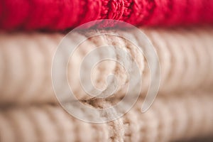 Stack of bright color knitted clothes on shelf in store close up.