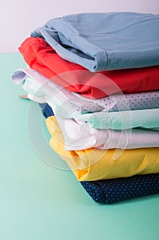 Stack of bright female trousers. Folded colorful pants and jeans. Close up