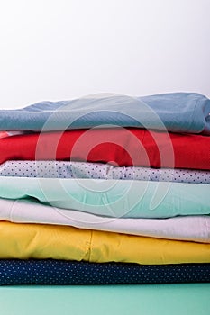 Stack of bright female trousers. Folded colorful pants and jeans. Close up