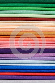 Stack of bright self-colored cotton fabrics as a background image