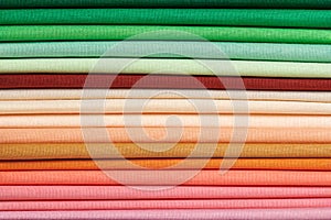Stack of bright self-colored cotton fabrics as a background image