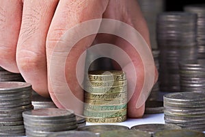 Stack of british pound coins with a male hand