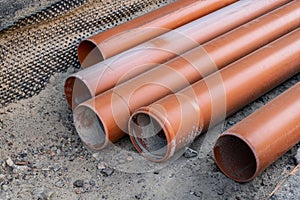 Stack of brown pvc pipes. Close up of orange plastic pipes on construction. Industrial background.