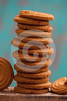 Stack of butter cookies/biscuits on wooden board with teal green rustic background photo