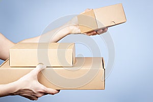 Stack of cardboard boxes in female hands. Blank parcel boxes on light blue background. Packaging, shopping, free