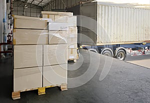 Stack of cardboard on pallet rack. Cargo trailer truck parked loading at dock warehouse. Cargo shipment. Freight truck transport.