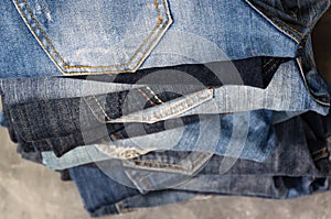 A stack of folded jeans on gray background. Close-up of jeans in different colors. Denim background. Selective focus