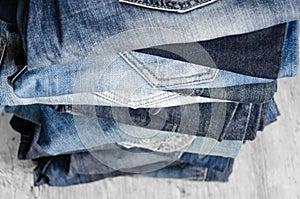 A stack of carelessly folded woman`s jeans on gray background. Close-up of jeans in different colors. Selective focus