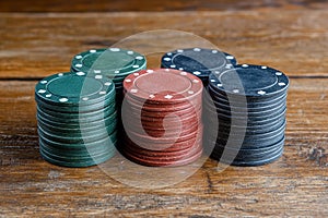 Stack of casino chips on wooden table.