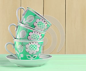 A stack of ceramic retro cups with red patterns on a pink wooden