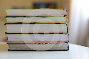 A stack of children's multi-colored books on a white table. Concept leisure, reading and education