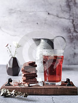 A stack of chocolate bars and a glass of drinks on a wooden board with background