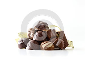 Stack of chocolate bonbons with golden ribbon white isolated background