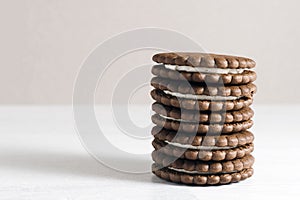 A stack of chocolate-cream cookies sits on the table.