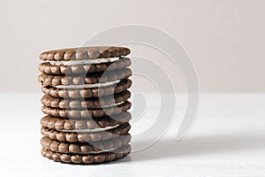 A stack of chocolate-cream cookies sits on the table.