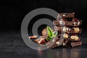 Stack of chocolate slices with mint leaf.Hazelnut and almond milk and dark chocolate pieces tower.Sweet food photo concept. The