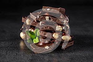 Stack of chocolate slices with mint leaf.Hazelnut and almond milk and dark chocolate pieces tower.Sweet food photo concept. The