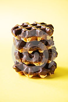 Stack of chocolate waffles. Close up and yellow background, copy space