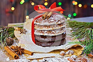 Stack of Christmas gingerbread rounds cookies tied with red ribbon icing sugar Xmas holiday table setting, decorated with garlands